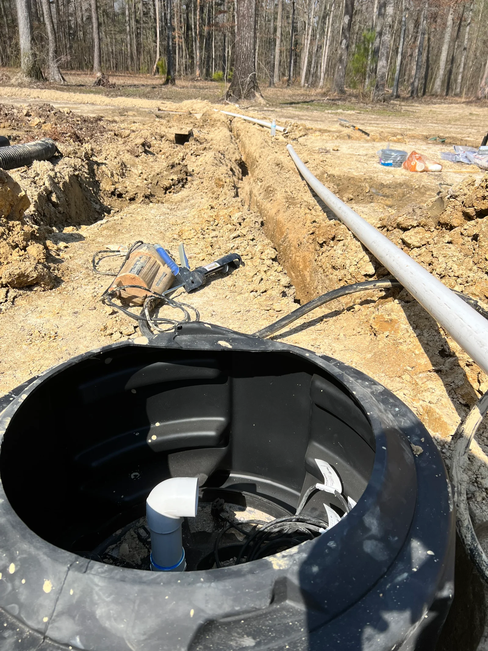 Septic tank installation with PVC piping and drainage field excavation