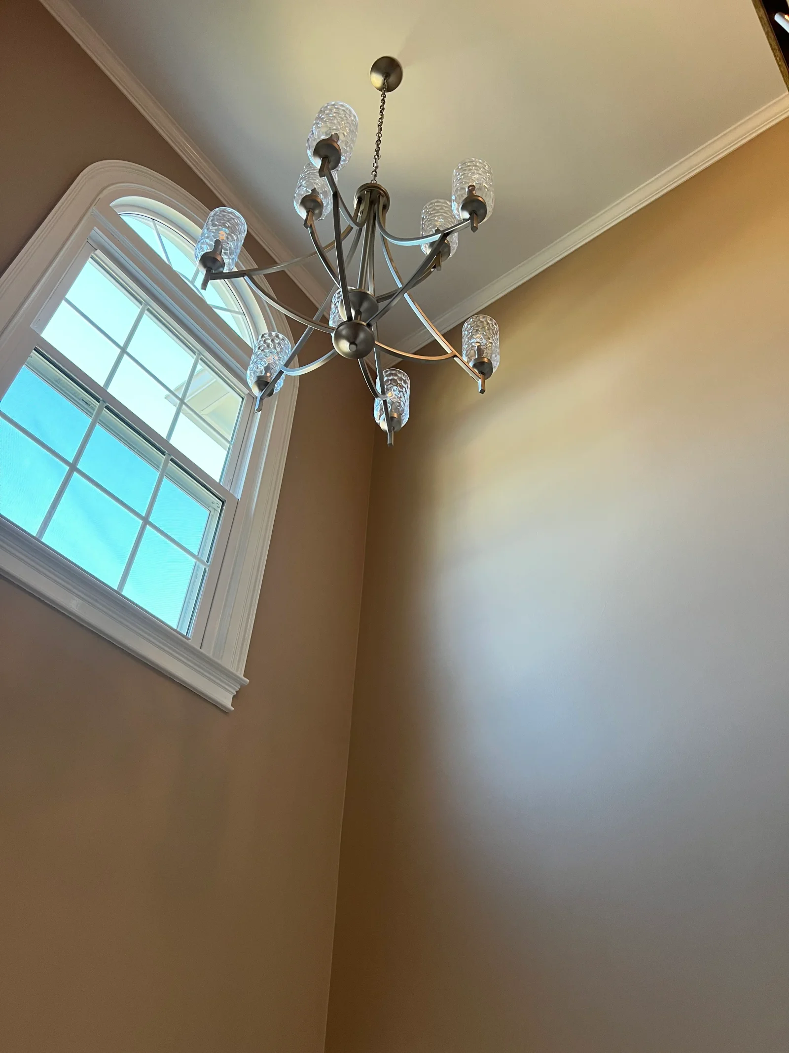 Multi-arm chandelier with crystal shades and brushed nickel finish installed in ceiling